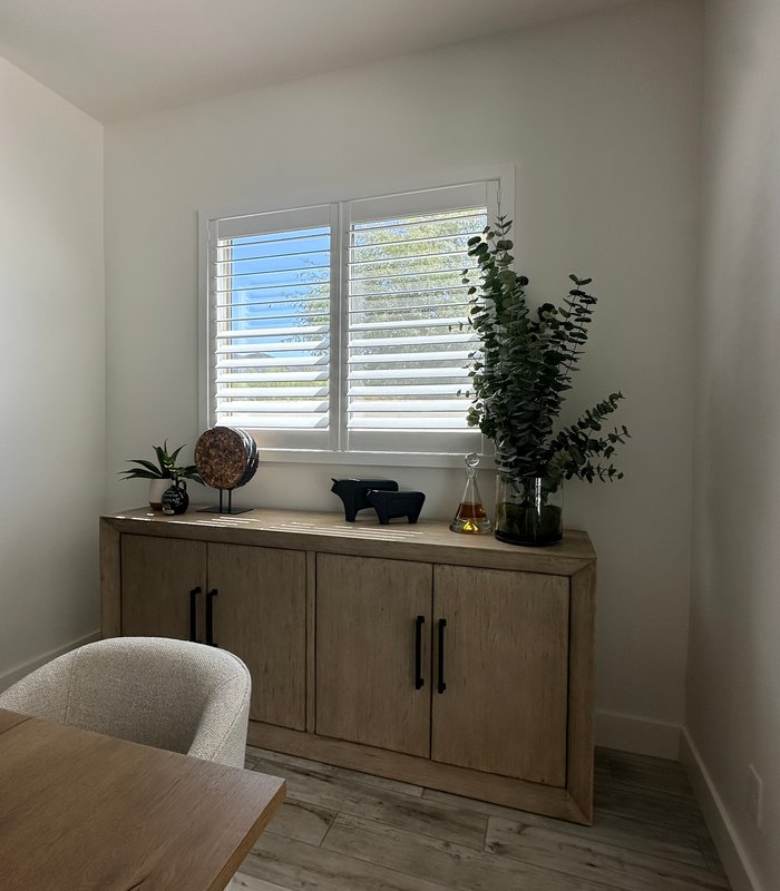 Dining room buffet below a white plantation-shuttered window