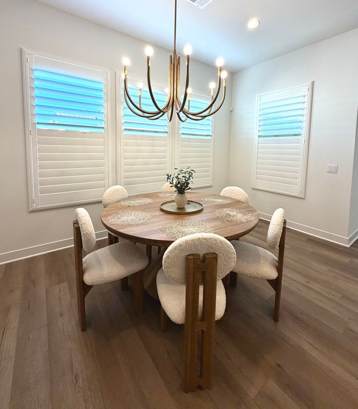 Dining nook with three Norman shutter panels, louvers tilted open to the Arizona sky